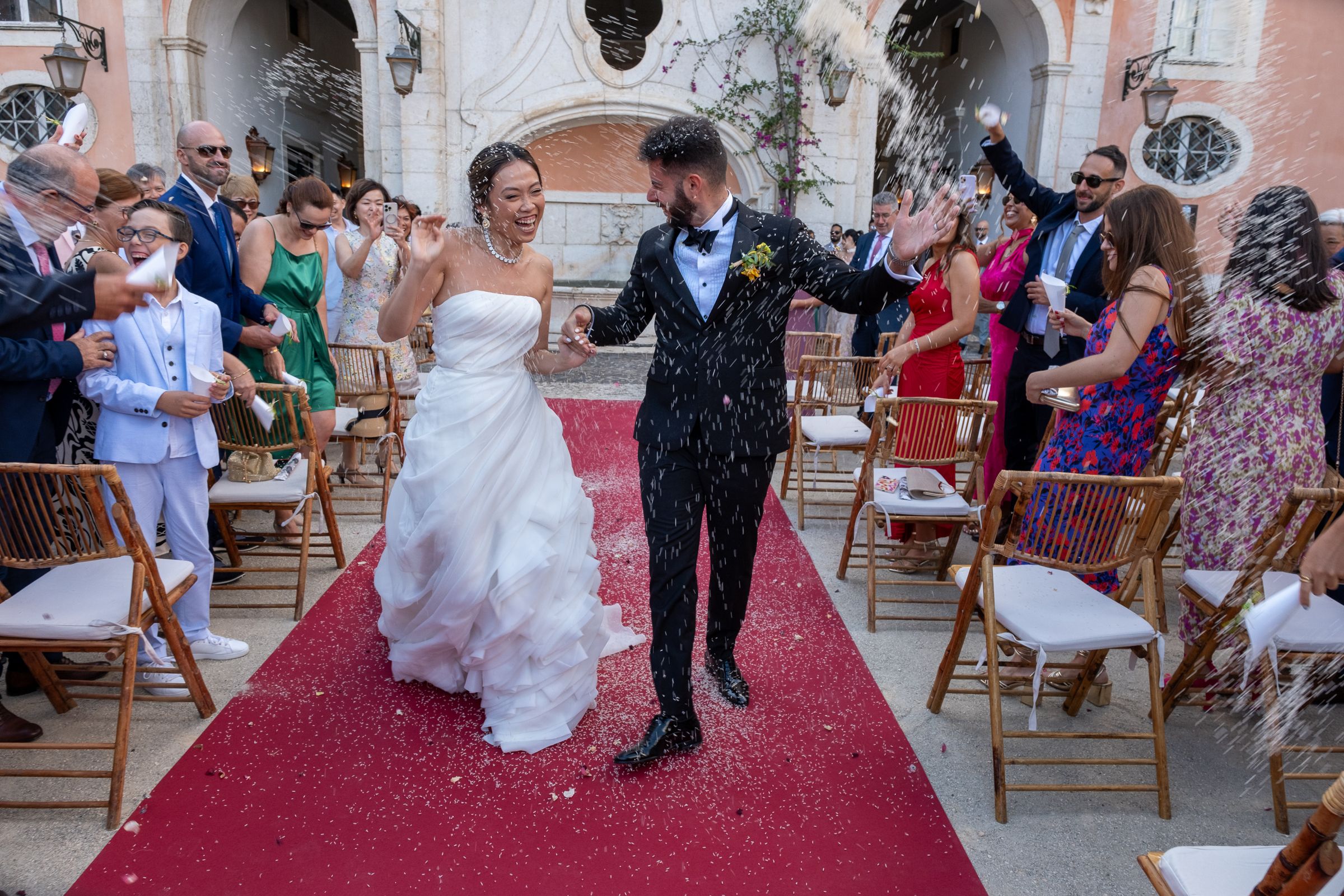 Wedding guests gathered on red carpet for an outdoor celebration.