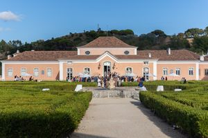 A panoramic view of a peach-colored estate building with manicured grounds.
