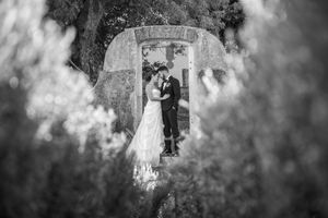 Artistic black and white wedding portrait against stone architecture.