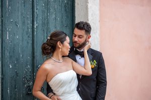 Wedding couple posing by teal wooden doors and pink walls.