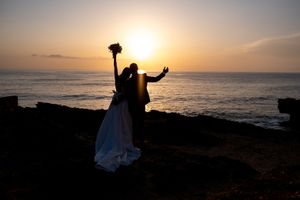 Dramatic sunset wedding photos with silhouettes against an ocean horizon.