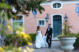 Wedding couple poses by pink mansion with decorative blue accents and lanterns.