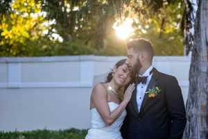 Sunset wedding portrait with golden light streaming through trees.