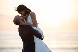 Silhouettes of couples embracing against a warm sunset ocean backdrop.