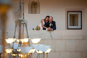 Wedding guests dance and celebrate inside a stone-walled reception venue with elegant chandeliers.