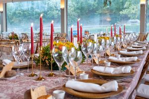 Elegant wedding reception table with red candles, fine china, and floral centerpieces.
