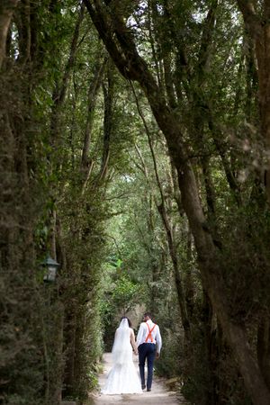 A romantic walk through a tree-covered pathway creates a magical wedding moment.