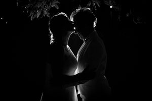Dramatic black and white silhouette of newlyweds embracing at their wedding reception.