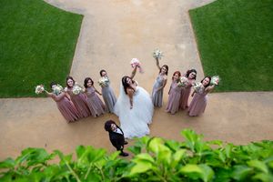 Aerial view of bridal party forming a circle on garden pathway with manicured lawns.
