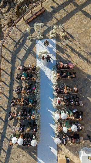 Aerial view of wedding guests arranged in a heart shape formation on stone pavement.
