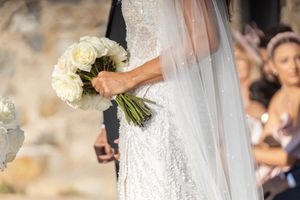 Bride holding classic white rose bouquet in detailed lace wedding gown.