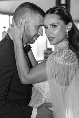 Intimate black and white portrait of couple in wedding attire sharing tender moment.