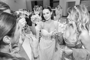 Wedding guests raise champagne glasses in a celebratory toast with the bride in an elegant white gown.