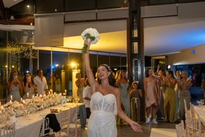 A bride in a stunning white dress celebrates at an elegantly decorated reception venue with glowing candlelight.