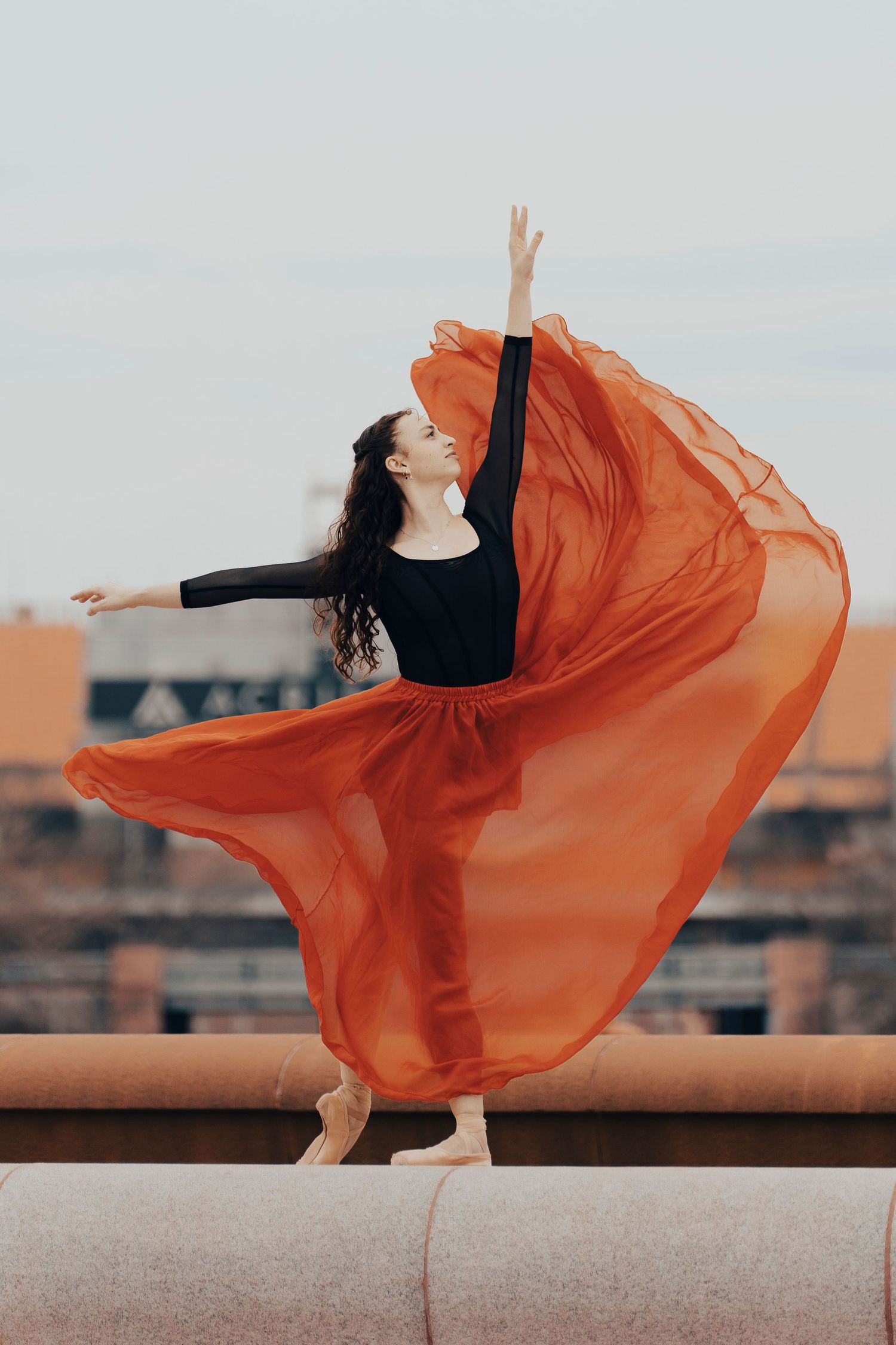 Graceful ballet dancer posing in front of Acrisure stadium at the Point State Park fountain at sunset
