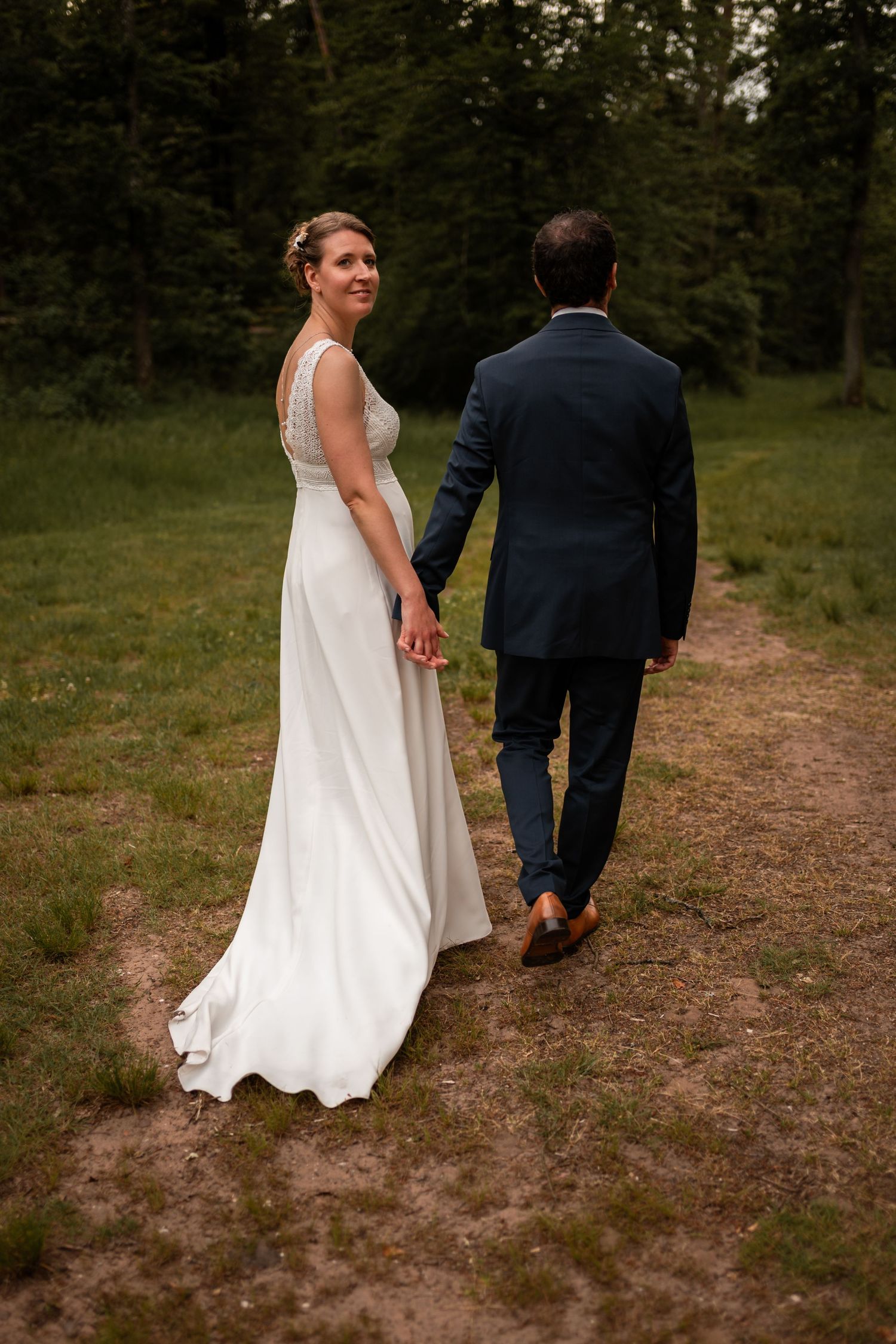 Maeva et Nicolas marchent main dans la main sous les arbres
