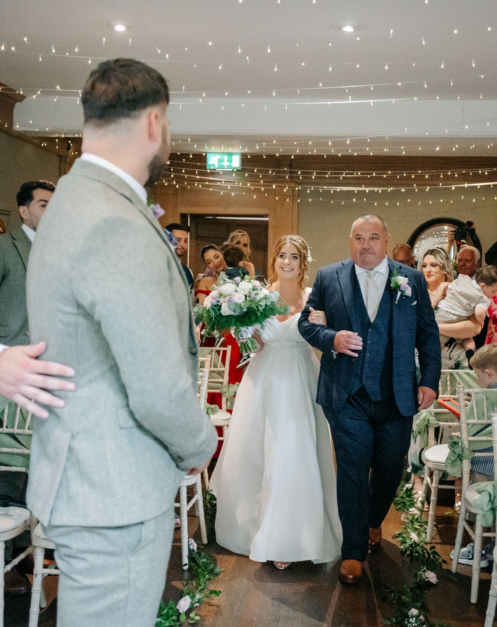 Wedding celebration in venue with fairy lights and guests dancing together on dance floor.