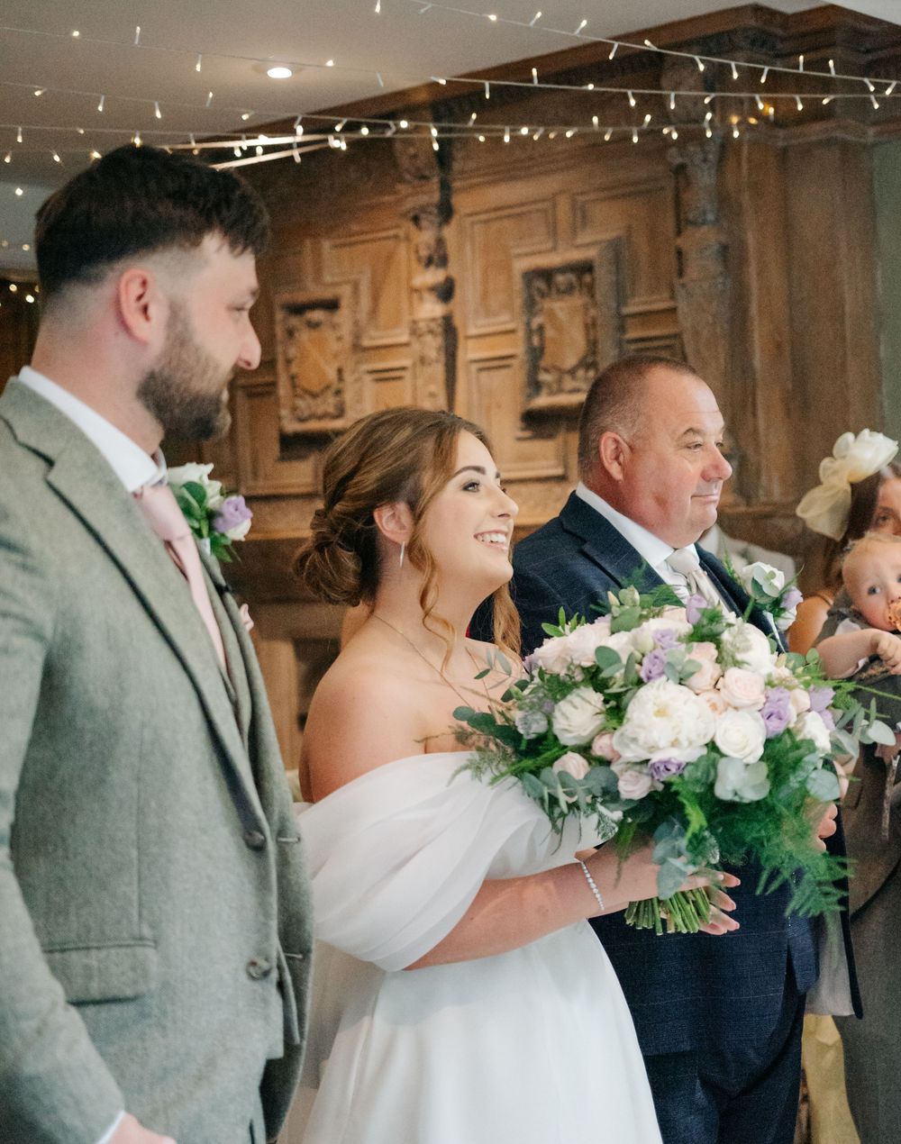 A joyful wedding scene with elegant floral bouquets featuring white and pink blooms under twinkling string lights.