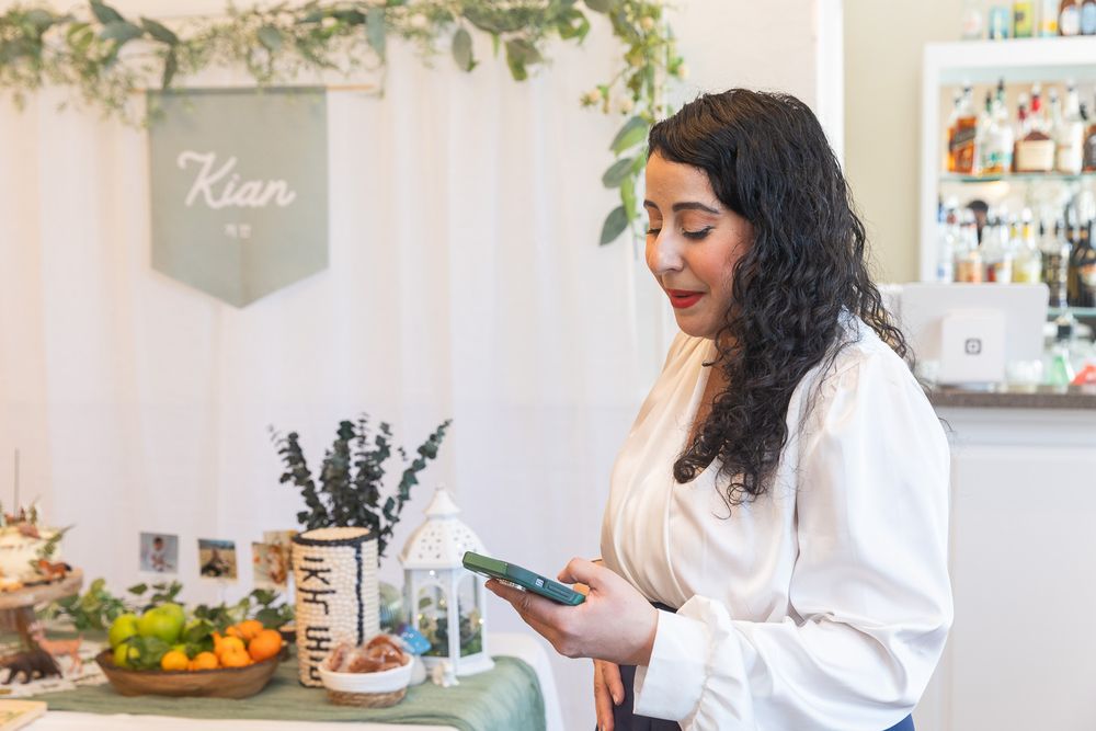 Someone uses their phone in a bright kitchen with dried lavender and citrus fruits on the counter.