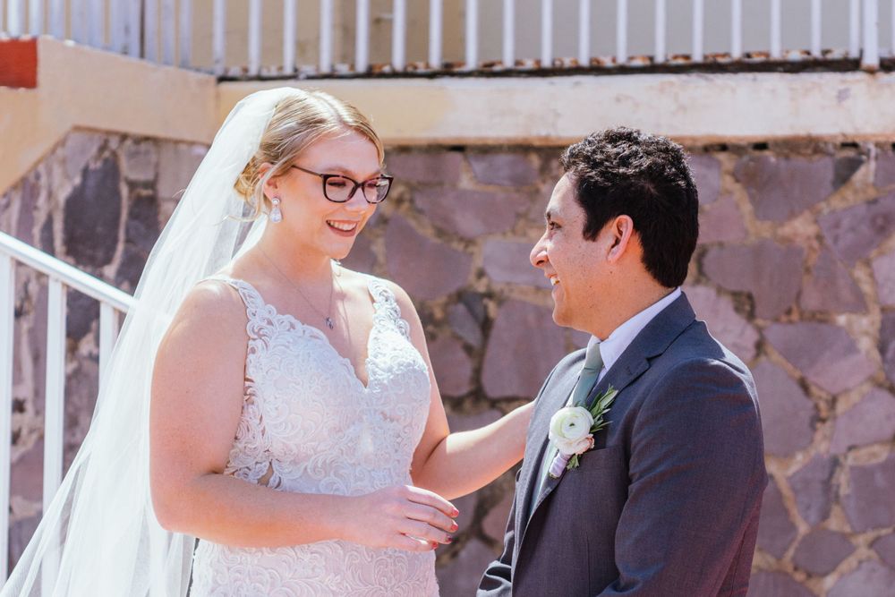 A couple shares an intimate moment during their outdoor wedding ceremony near a stone wall backdrop.