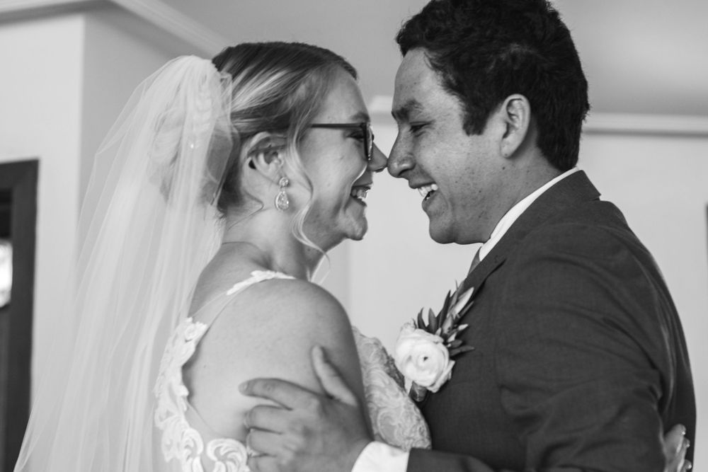 A black and white wedding photo showing a tender moment between newlyweds sharing a joyful intimate embrace.