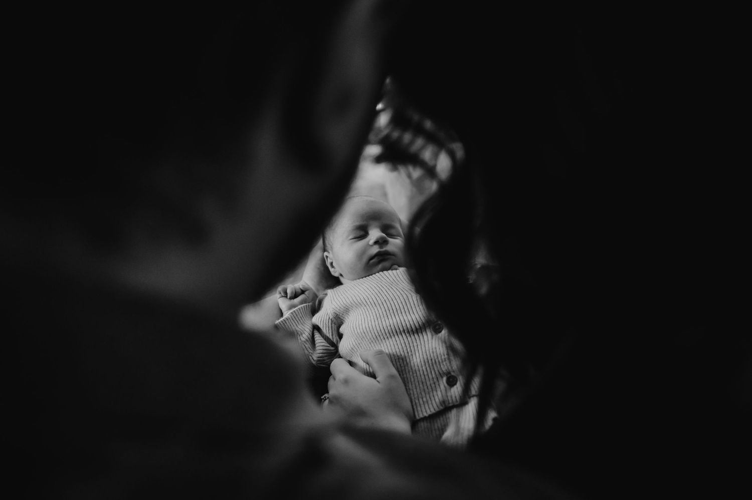 A black and white photograph shows a sleeping infant with soft lighting creating a dreamy atmosphere.