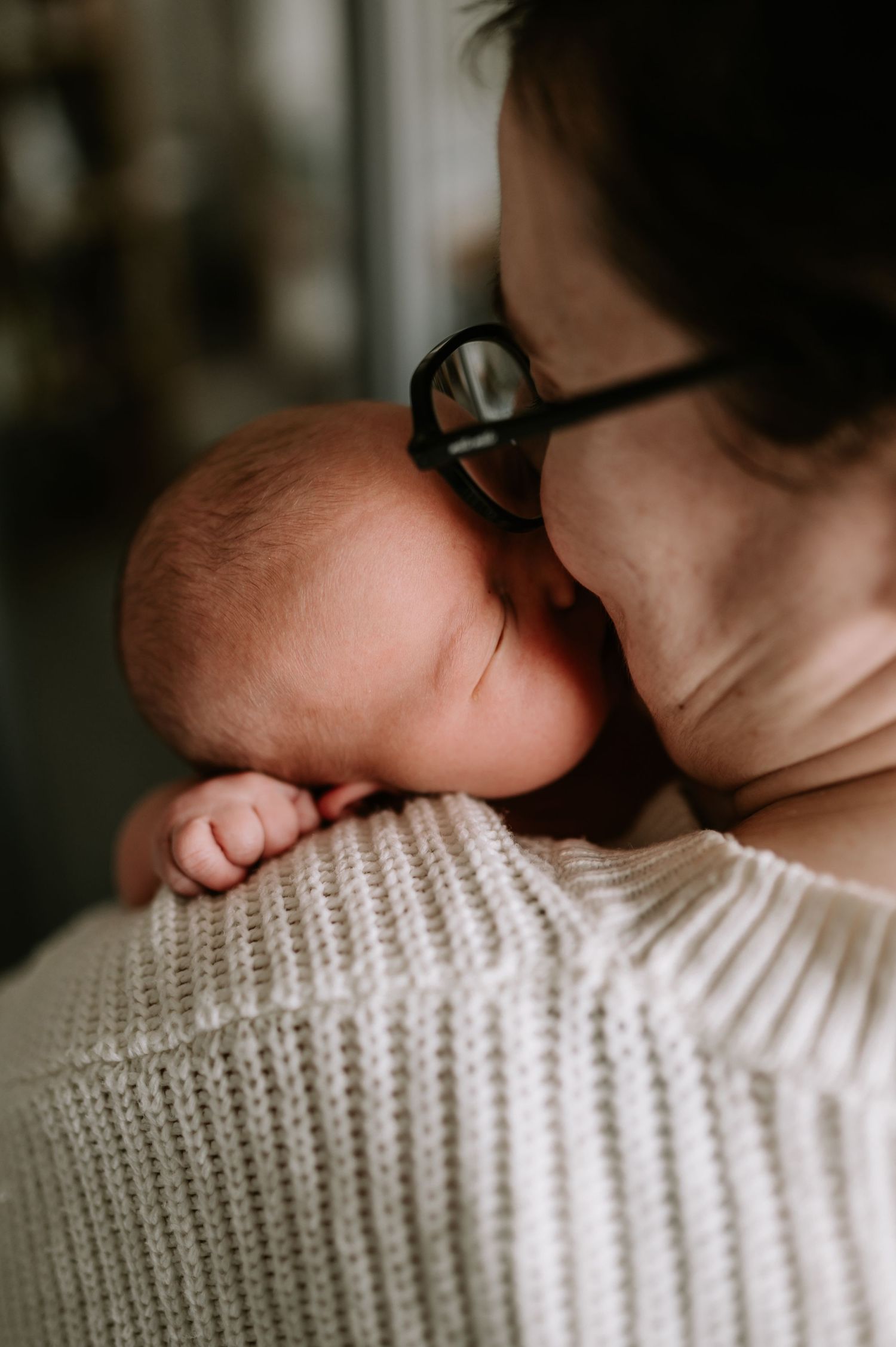 A sleeping baby rests against a warm knit sweater in a tender embrace.