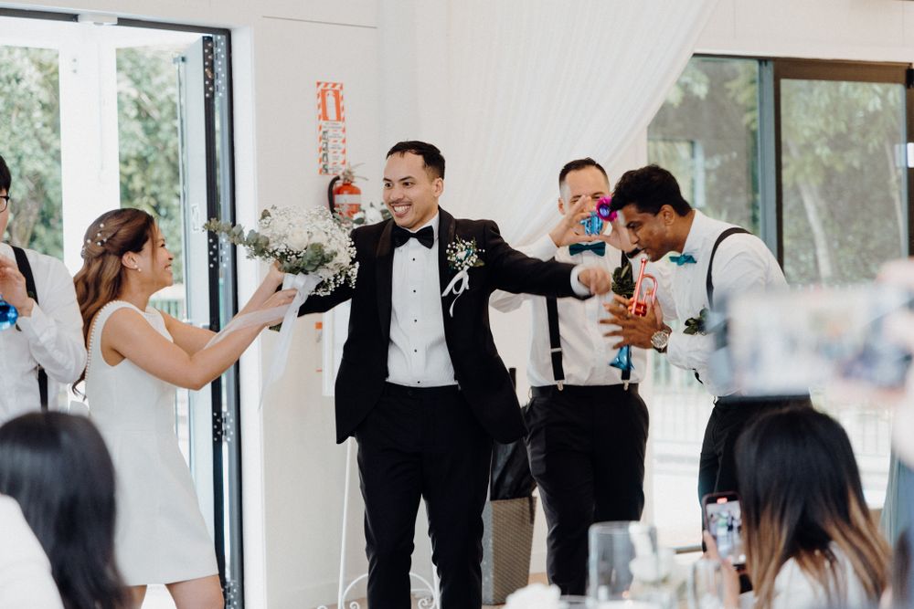 Wedding party celebrates with drinks and laughter during a joyful reception captured by Apertured Media Auckland Wedding Photographer.