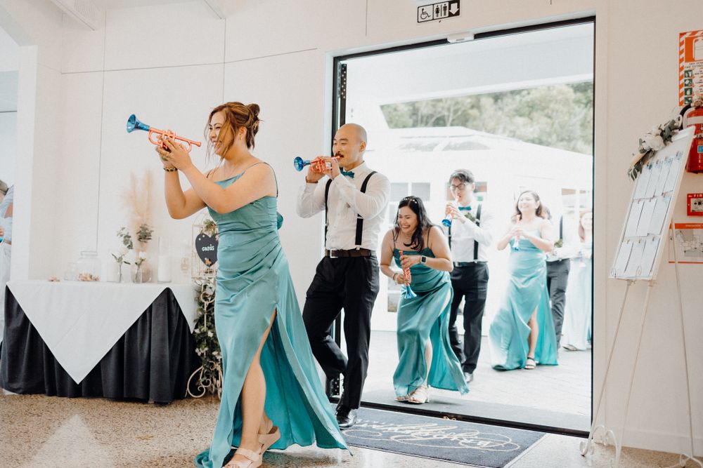 Wedding party members dance through an entrance captured by Apertured Media Auckland Wedding Photographer.