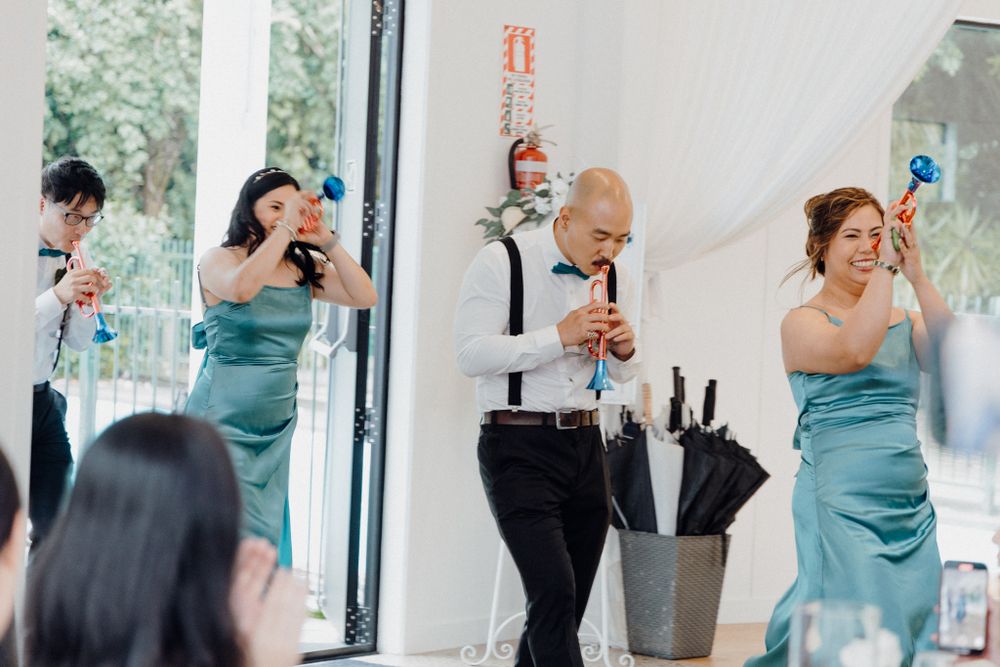 People in turquoise bridesmaid dresses laugh while doing their entrance captured by Apertured Media Auckland Wedding Photographer.