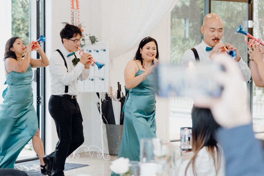 Wedding guests in teal bridesmaid dresses and formal attire celebrate joyfully captured by Apertured Media Auckland Wedding Photographer.