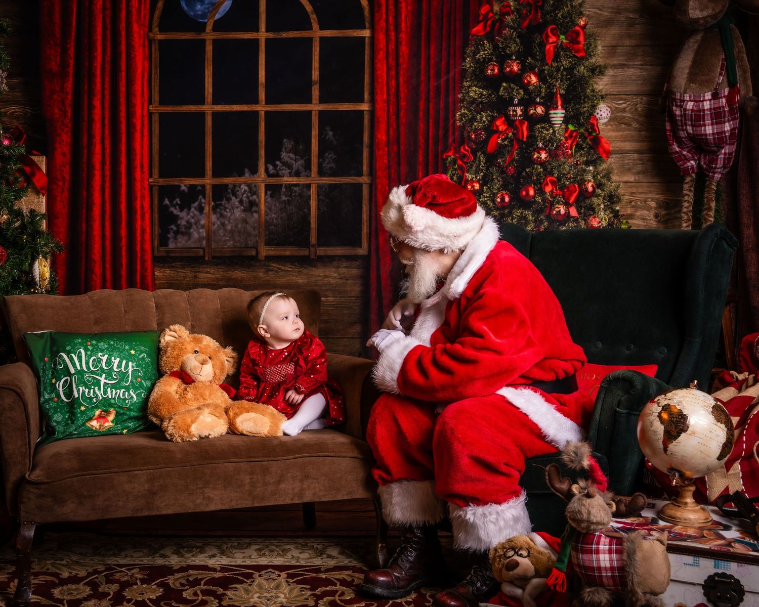 Santa sits on a brown couch near a decorated Christmas tree with stuffed animals and festive decor.