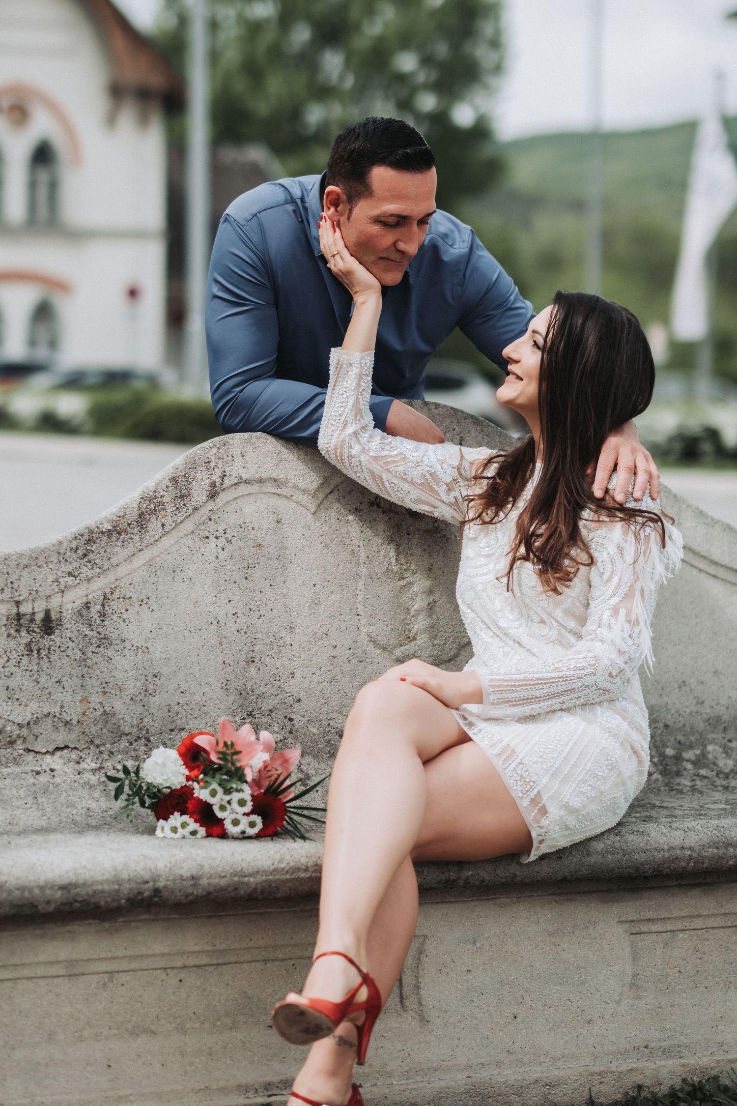 A sweet moment shared on a stone bench with a bouquet of flowers nearby.