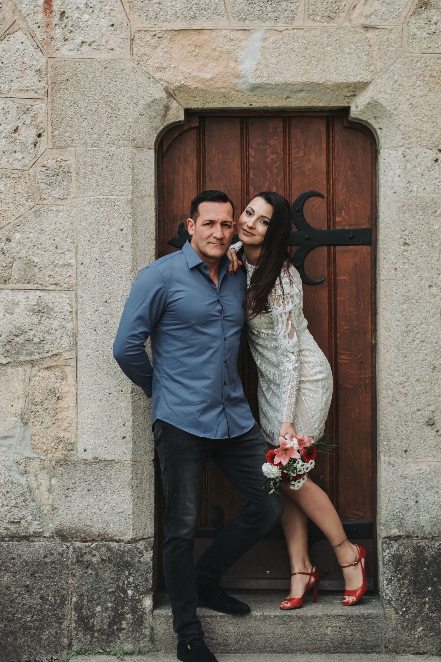 A couple shares a tender moment in a historic stone doorway.