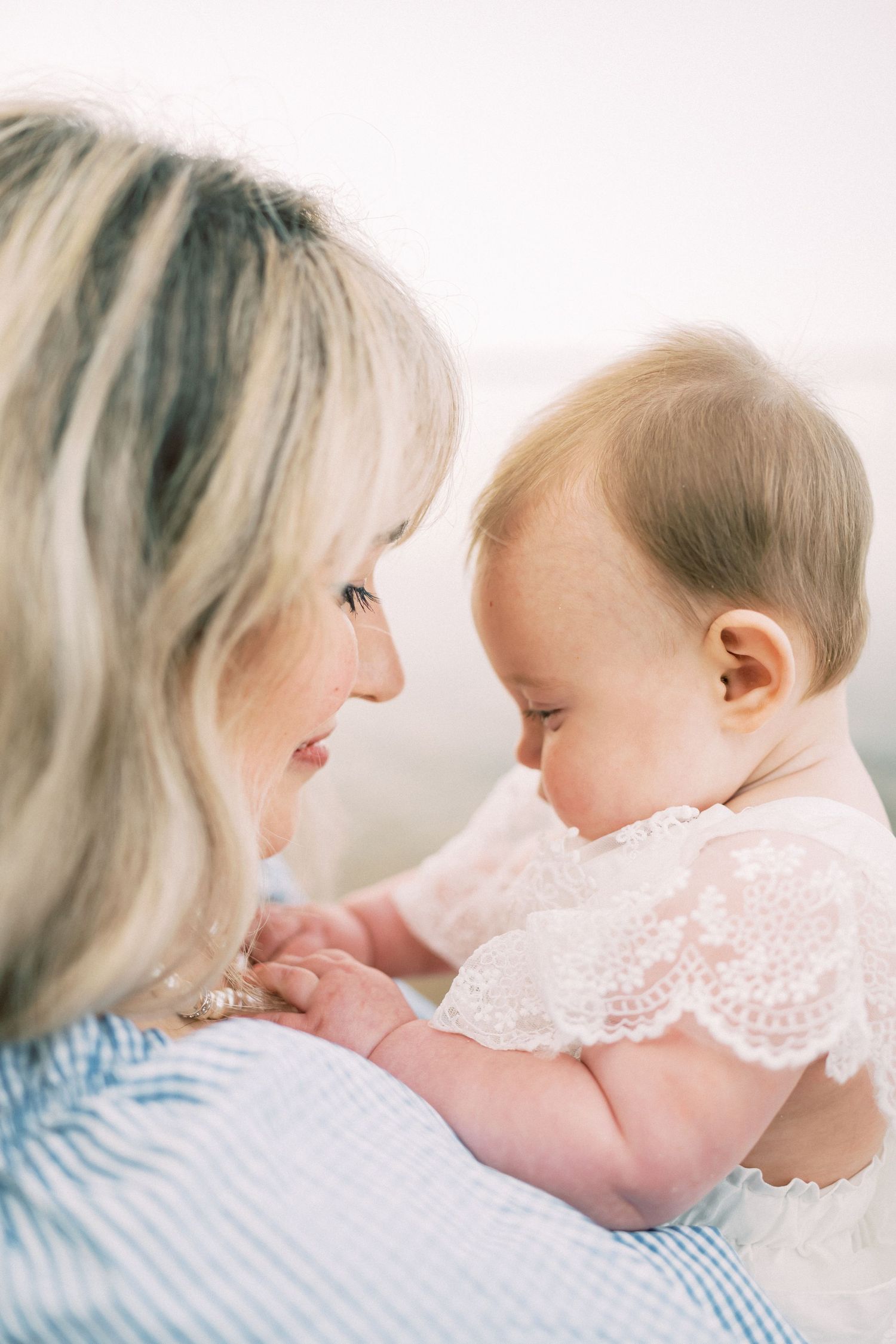 Intimate parenting moment captured in soft lighting as adult and baby share close interaction.