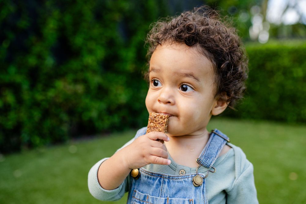 Young toddler in denim overalls enjoying an ice cream cone outdoors.