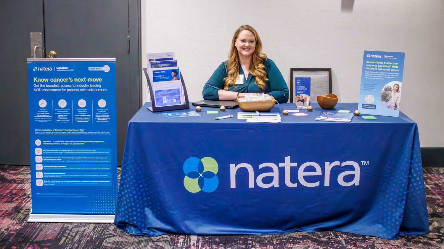 A professional trade show booth display with blue banners and marketing materials on a table.