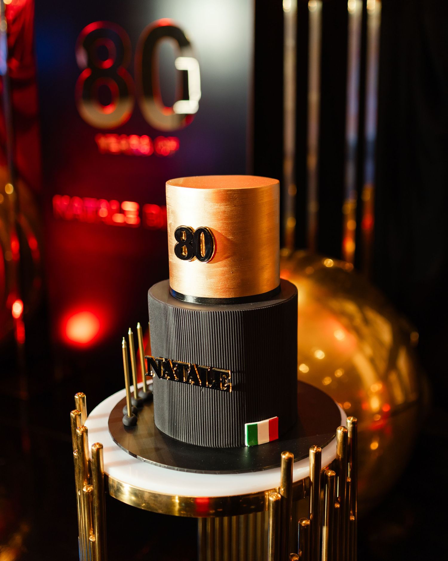 Modern three-tiered gold and black birthday cake with metallic accents and the number 30 on display.