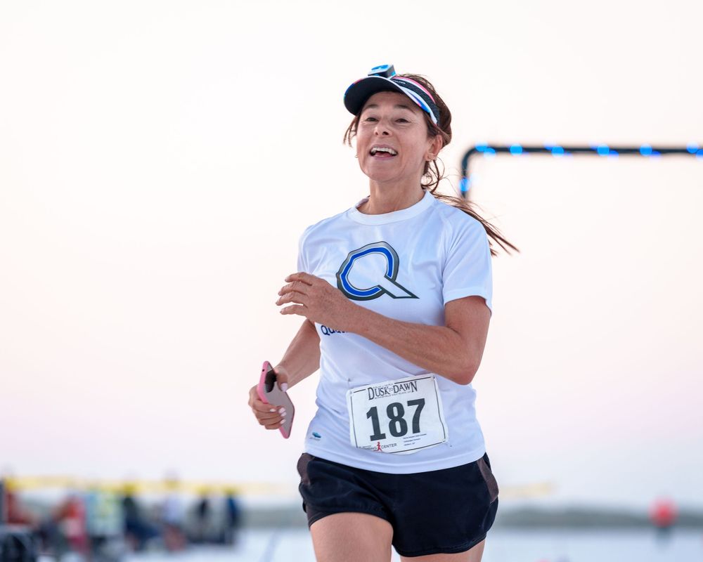 Trail race runner charging uphill on rugged terrain with mountain views, showcasing competitive trail running.