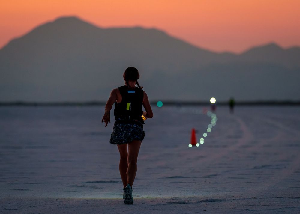 Trail race runner charging uphill on rugged terrain with mountain views, showcasing competitive trail running.