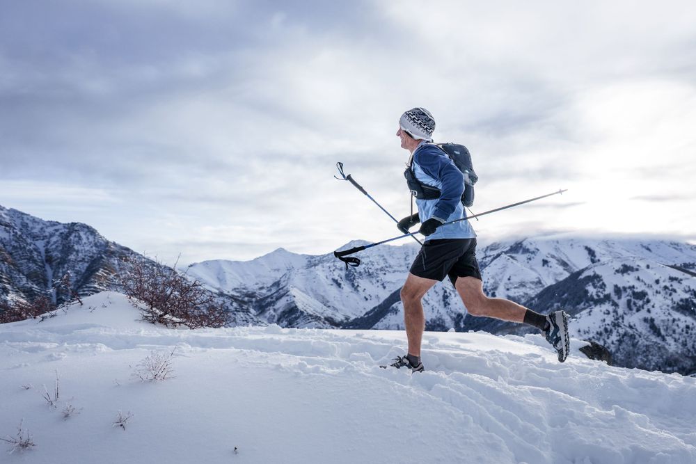 Trail race runner charging uphill on rugged terrain with mountain views, showcasing competitive trail running.