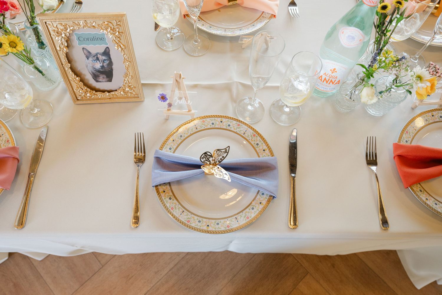 Elegant place settings on a long table decorated with floral arrangements and delicate china plates for a formal event.