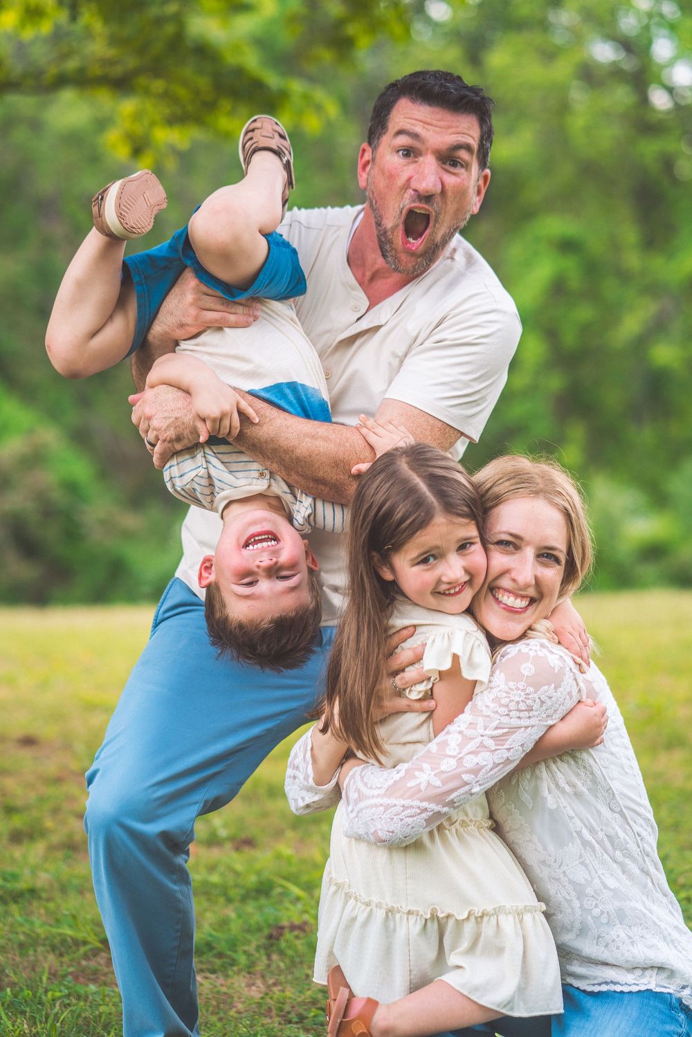 Energetic family portrait outdoors showing playful poses and laughter in a grassy field.