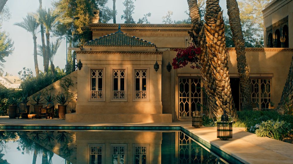 Horizontal panoramic view of a luxury estate's facade with palm trees and architectural details.
