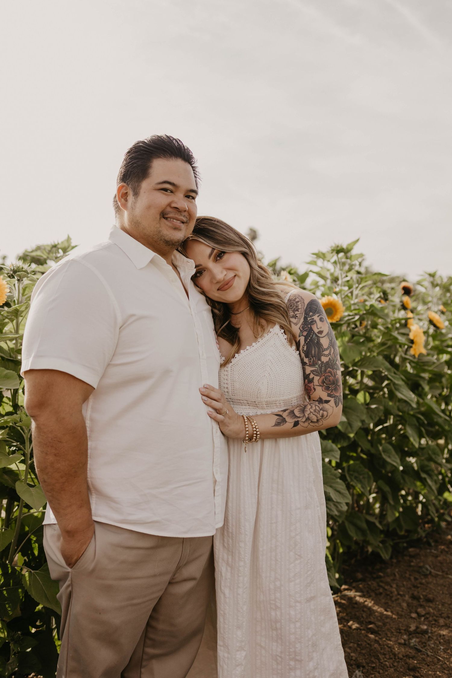 A family poses together outdoors in coordinating white and neutral outfits during a warm sunset photoshoot.