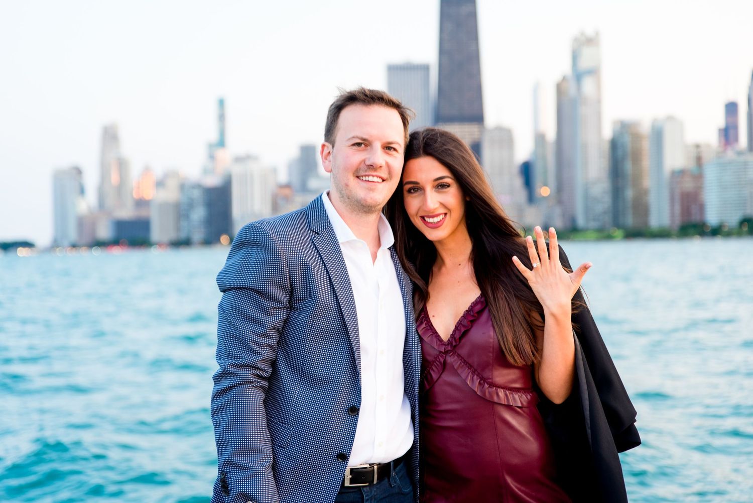 man and woman smiling together and woman holding up hand in front of skyline after Chicago Proposal