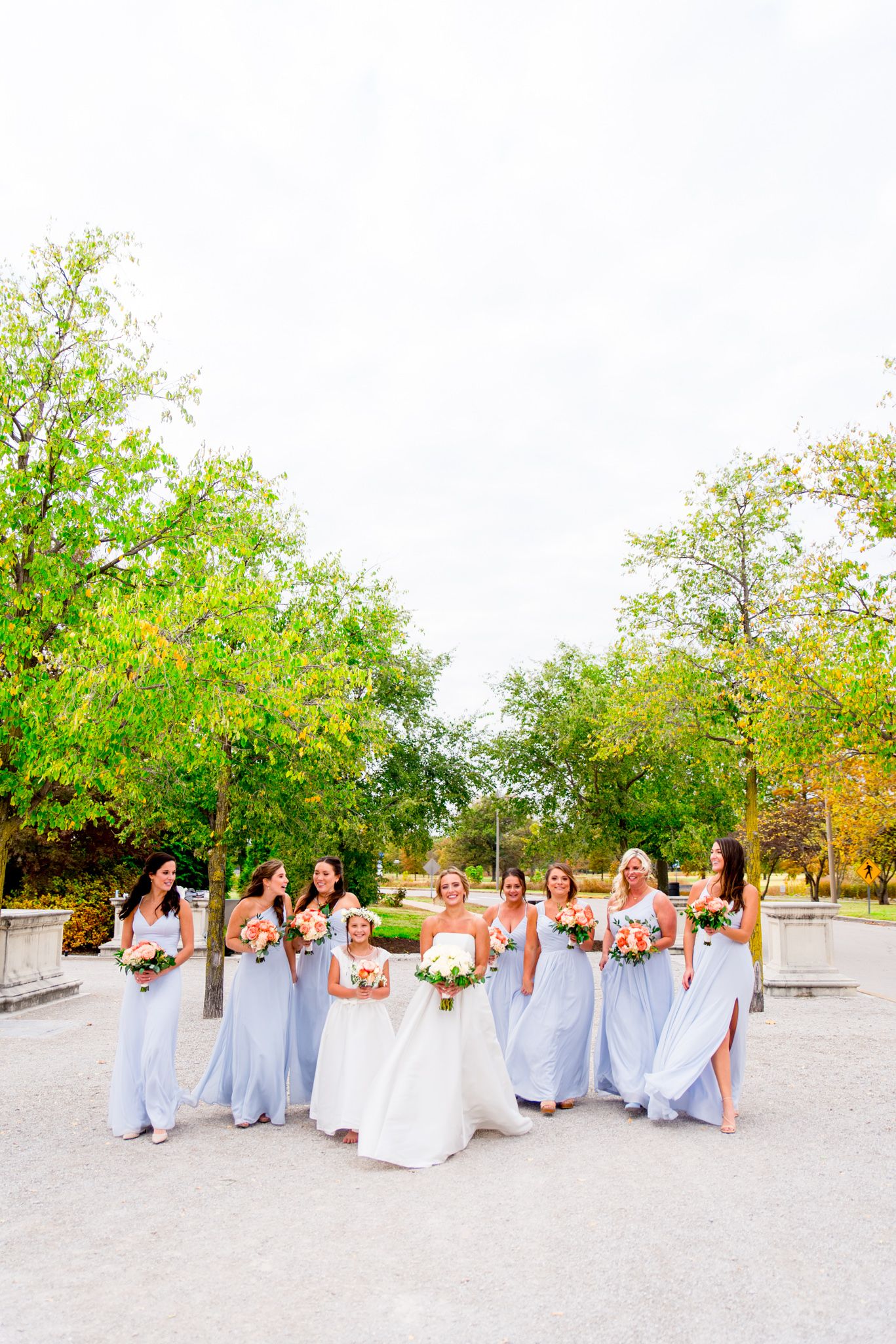 bride laughs with bridesmaids in light blue dresses and coral bouquets at STL Forest Park fall wedding