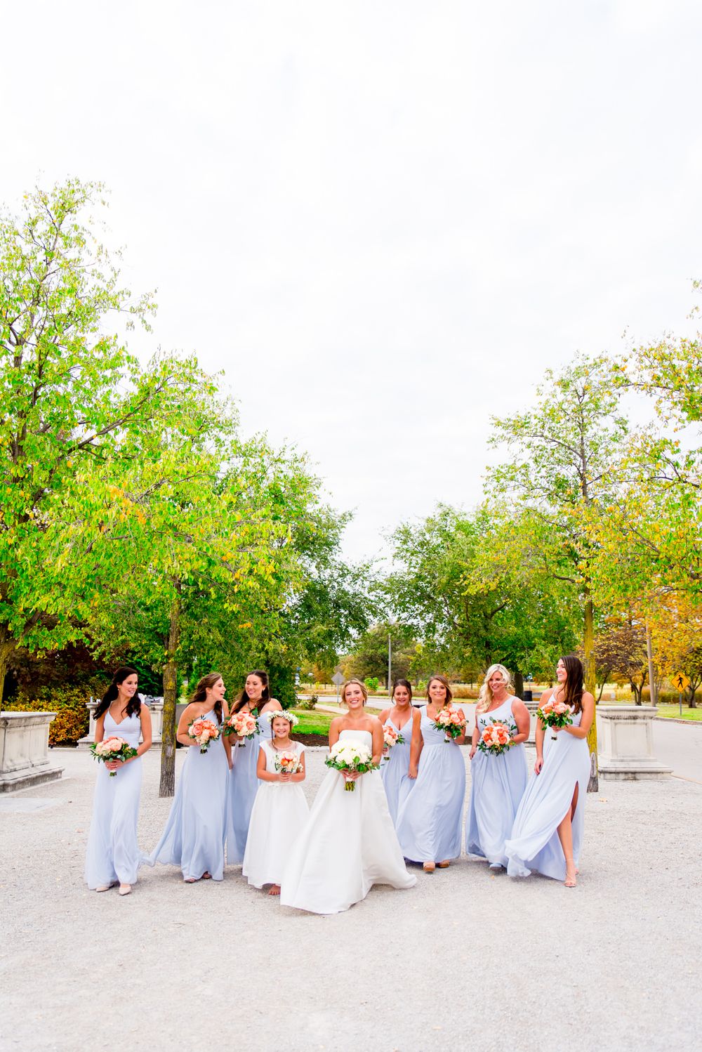 bride laughs with bridesmaids in light blue dresses and coral bouquets at STL Forest Park fall wedding