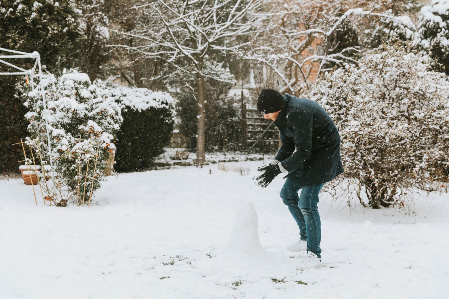 man building snowman in garden
