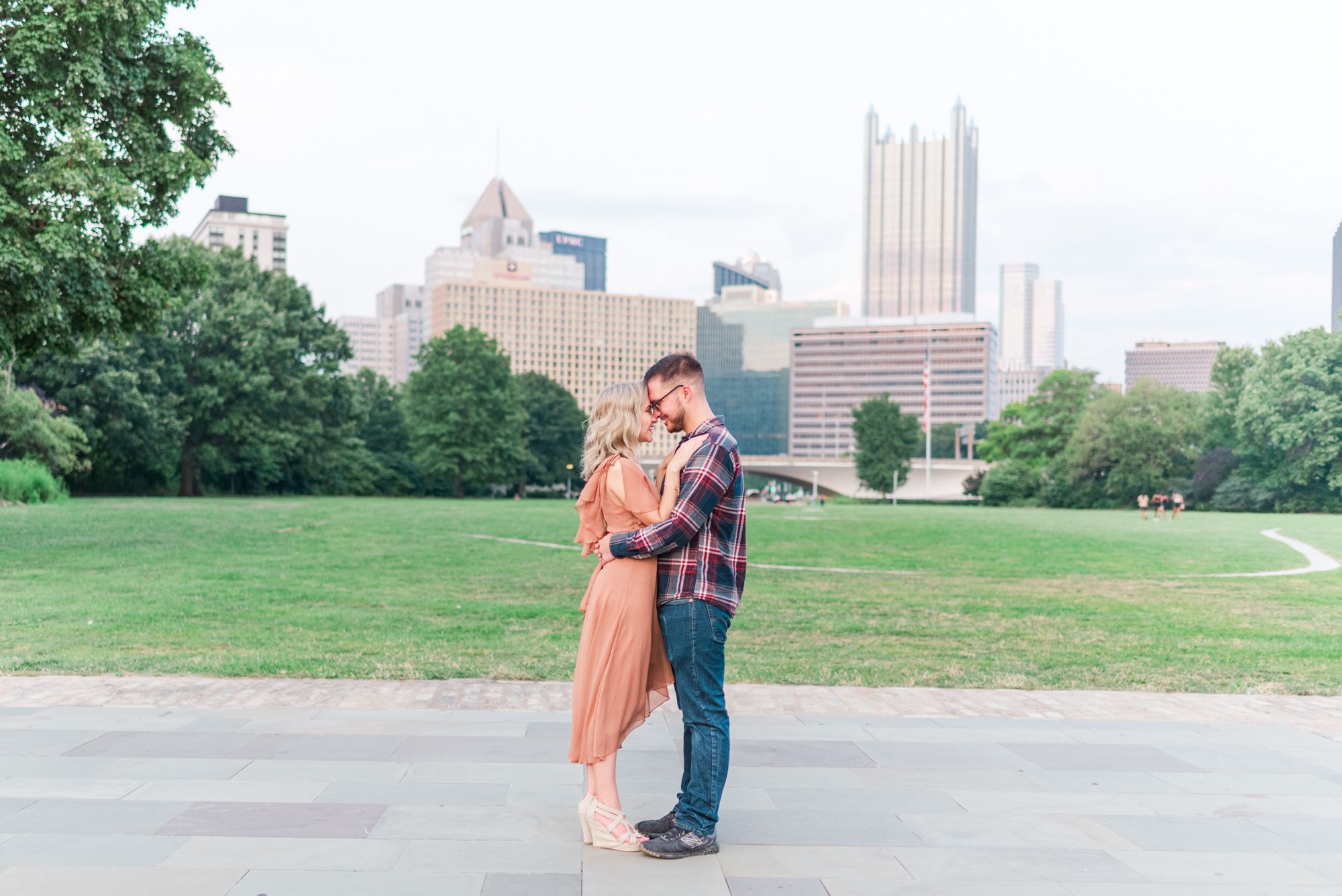 Newly engaged couple with city skyline at Point State Park in Pittsburgh, Pennsylvania